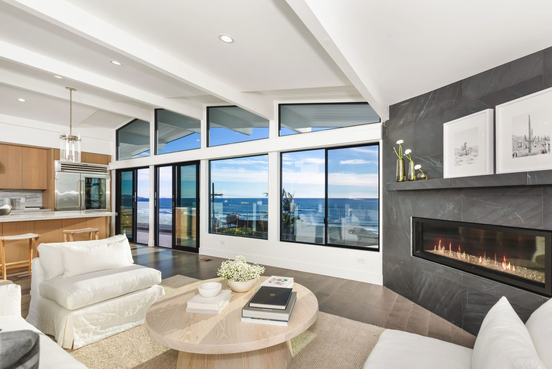 a modern living room with a fireplace and clear views of the coastline during daytime.