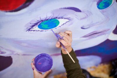 Female painter draws picture with paintbrush