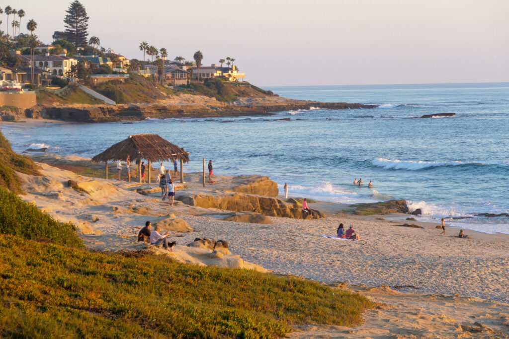 A few tourist and and a tiki shack at the Windansea Beach in La Jolla, San Diego, California during sunset