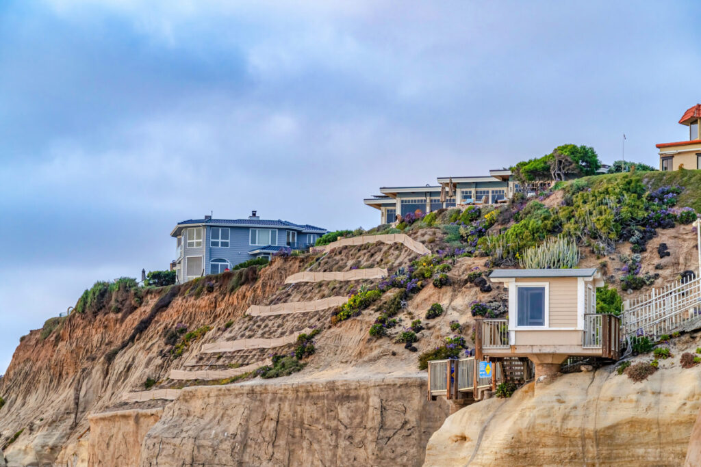 Waterfront homes on mountain with cloudy sky background in San Diego California. Real estate properties on coastal landscape at ocean front.