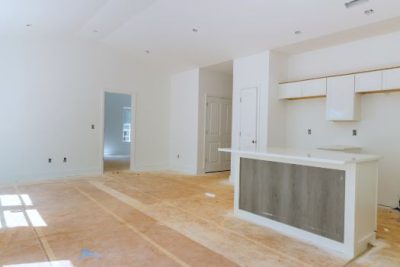 Newly built home interior under construction with unfinished flooring and a modern white kitchen island.