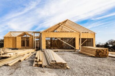 Wood frame of a new home under construction with lumber stacked in front, symbolizing growing builder activity in 2025.
