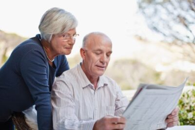 Older couple reviewing real estate or financial documents together outdoors.