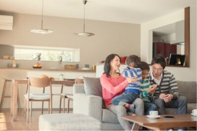 Happy family sitting on a couch in their new home, enjoying time together after buying a house in October.